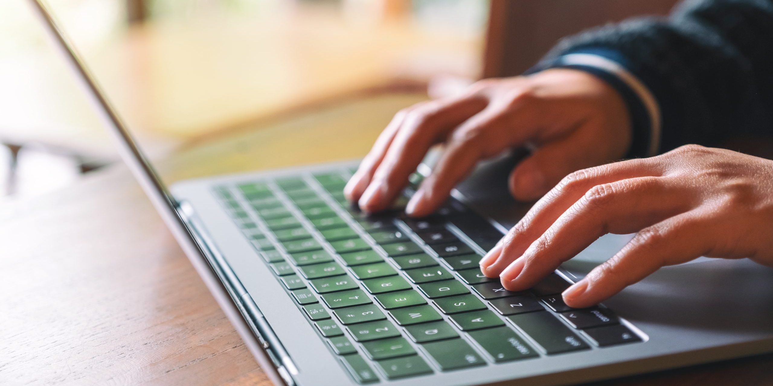 Closeup image of hands using and typing on laptop computer keyboard on the table